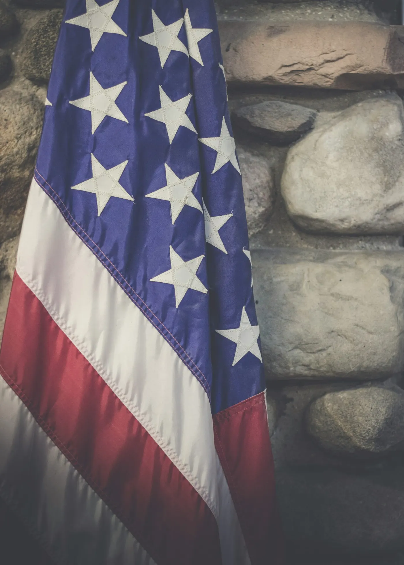 American flag draped against a stone wall